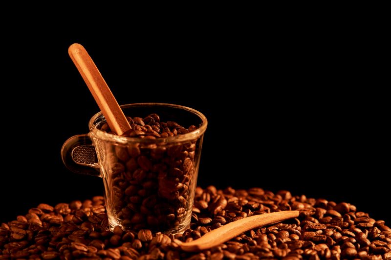 Tasse de café rempli de grains non moulus accompanée d'une touillette comestible à base de biscuit spéculoos plongée dans la tasse